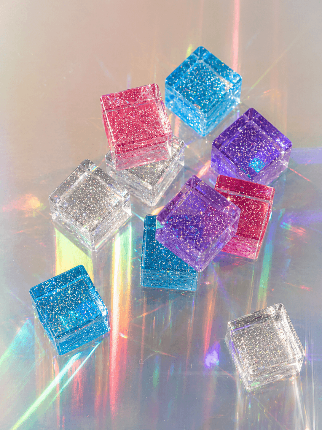 Colorful cosmic cube acrylic glitter blocks arranged with reflections and sparkle.