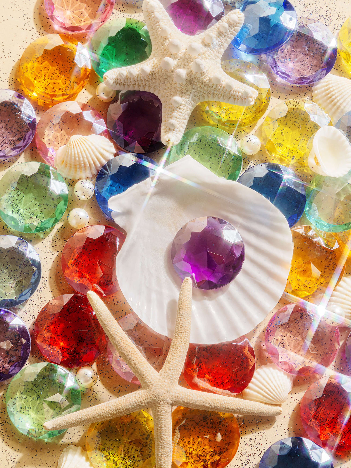Beautiful display of Magic holographic acrylic gems and seashells with sparkling reflections and vibrant colors.