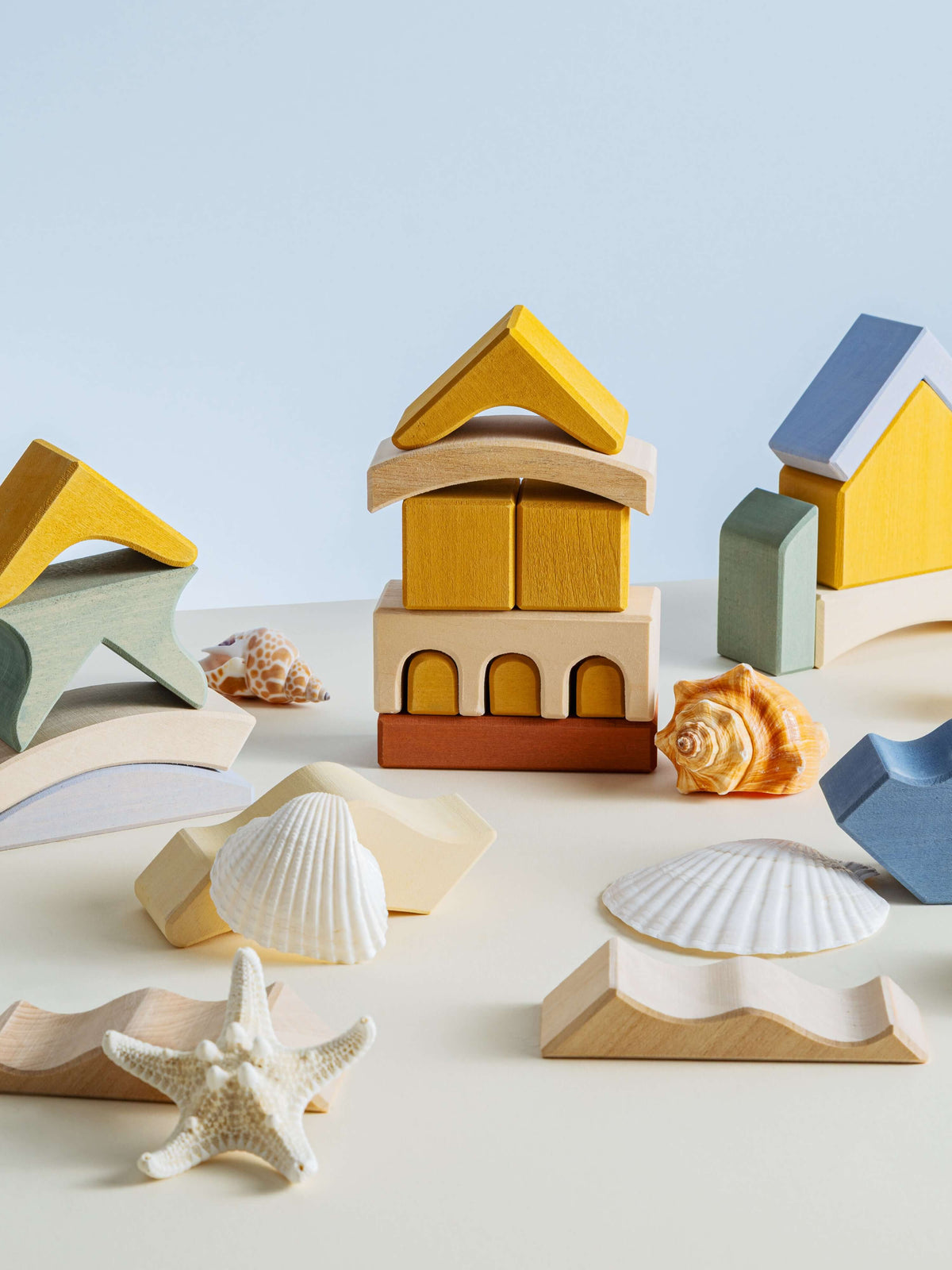 Colorful wooden building blocks and shells creating a stack, inspired by the Malibu Puzzle design.