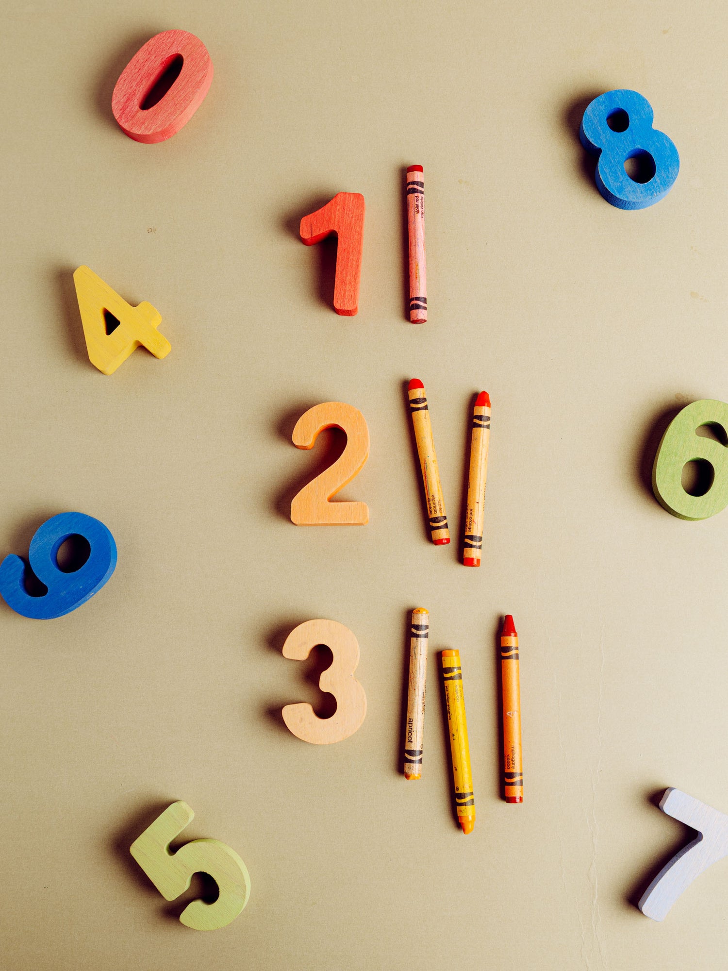Colorful wooden numbers 0-8 and crayons, highlighting the fun of an educational puzzle set.