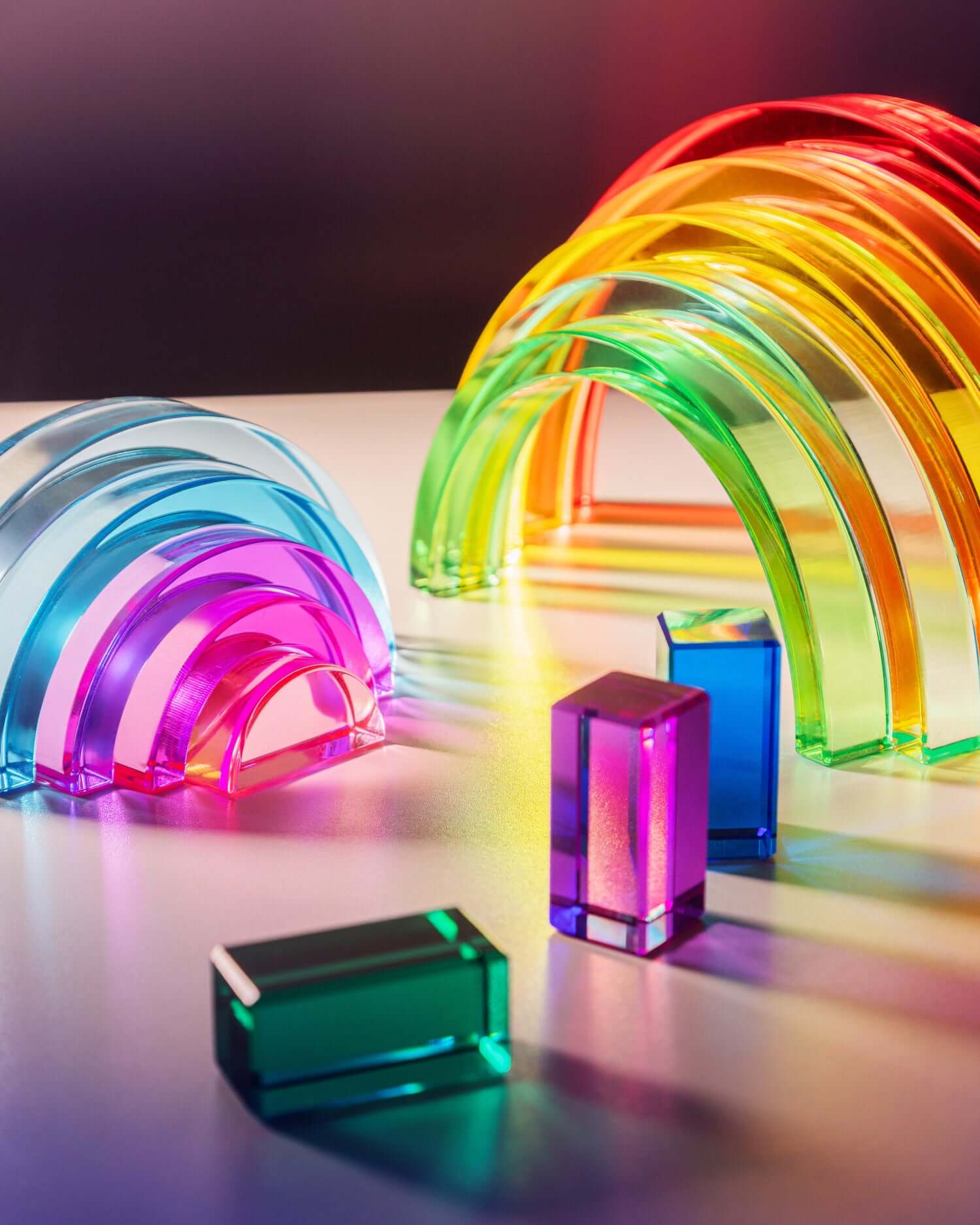 Lucid Rainbow stacking toy with vibrant translucent arches and geometric shapes reflecting light.