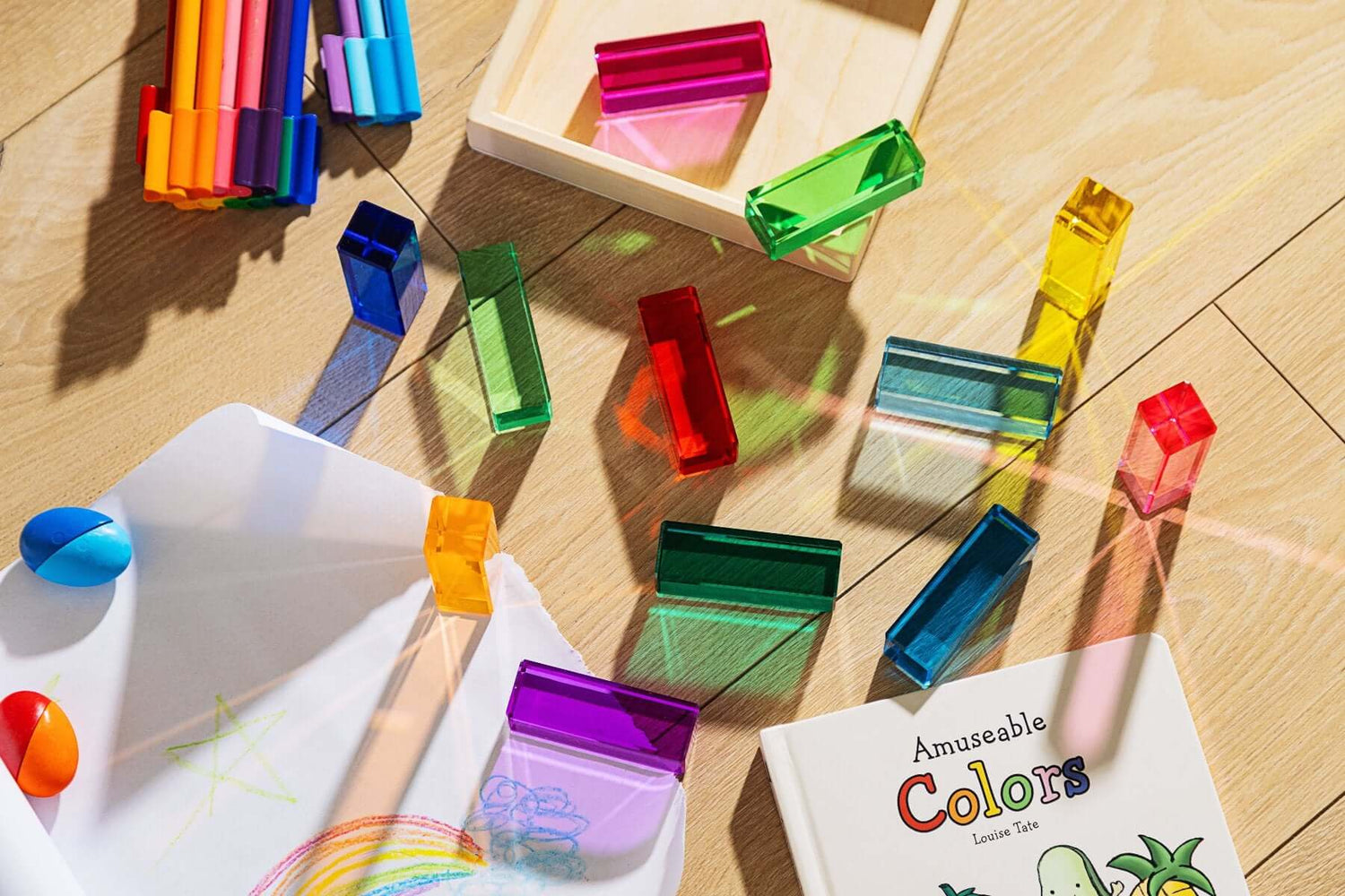 Noa Blocks 12 translucent rainbow building blocks reflecting light on wooden floor sensory color play