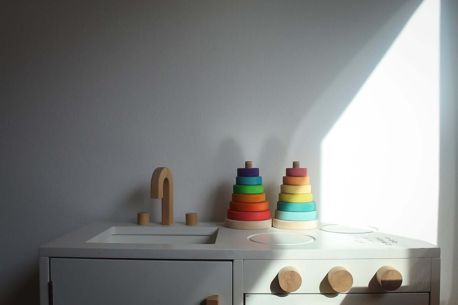 Suki Stacking Tower wooden rainbow stacking rings toy in primary colors on kids play table, toddler fine motor skills