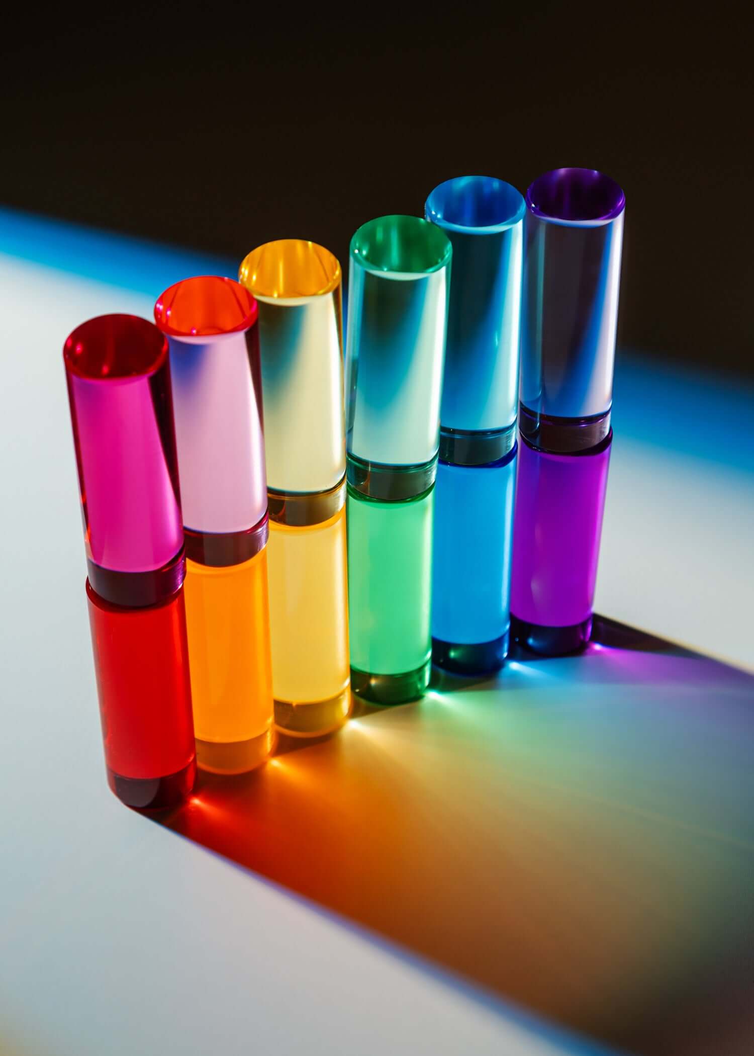 Set of colorful cylindrical objects on a reflective surface with a dark background