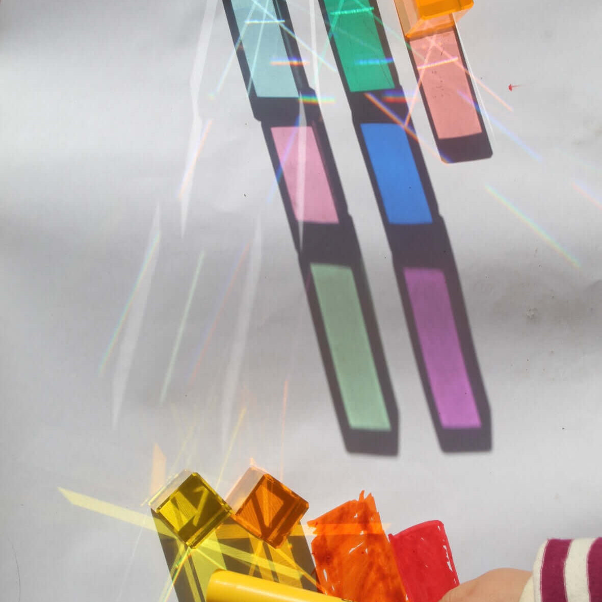 Translucent cubes making rainbow shadows on white paper