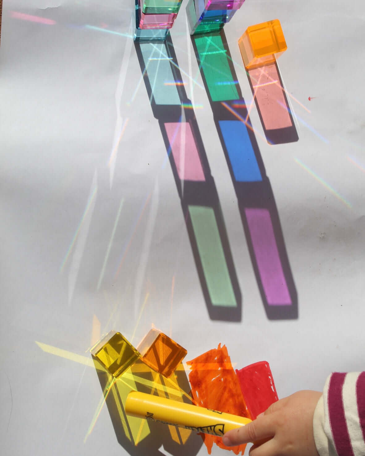 Translucent cubes making rainbow shadows on white paper