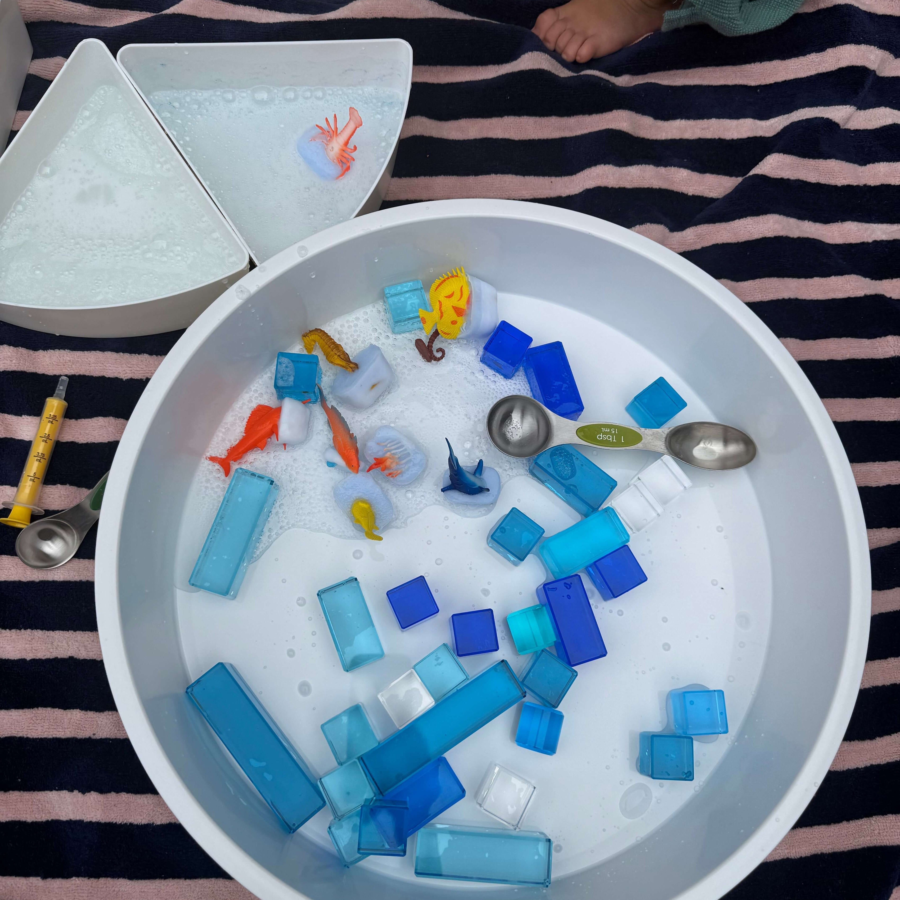 Summer Water Play Ideas for Kids with colorful toys and blocks in a tub filled with soapy water.