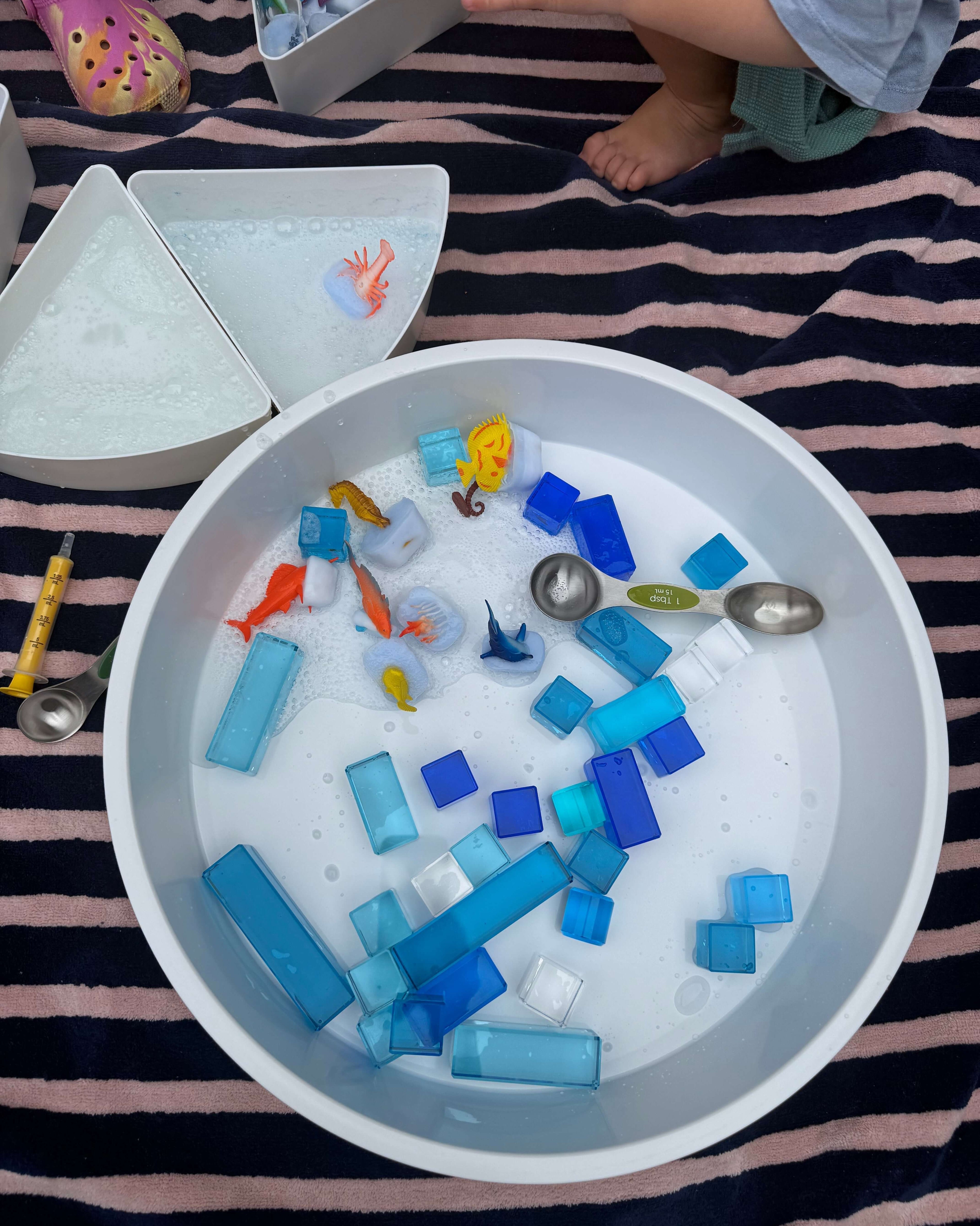 Summer Water Play Ideas for Kids with colorful toys and blocks in a tub filled with soapy water.