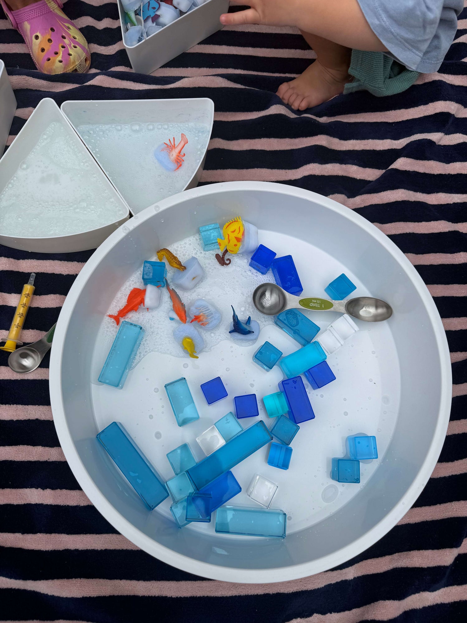 Summer Water Play Ideas for Kids with colorful toys and blocks in a tub filled with soapy water.