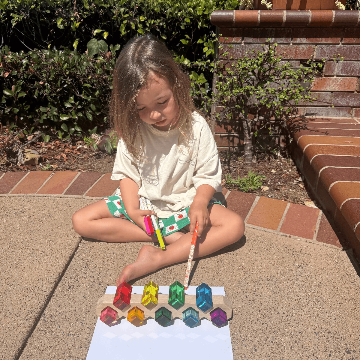 A toddler engaging in screen-free summer activities for toddlers, playing with colorful toys outdoors.