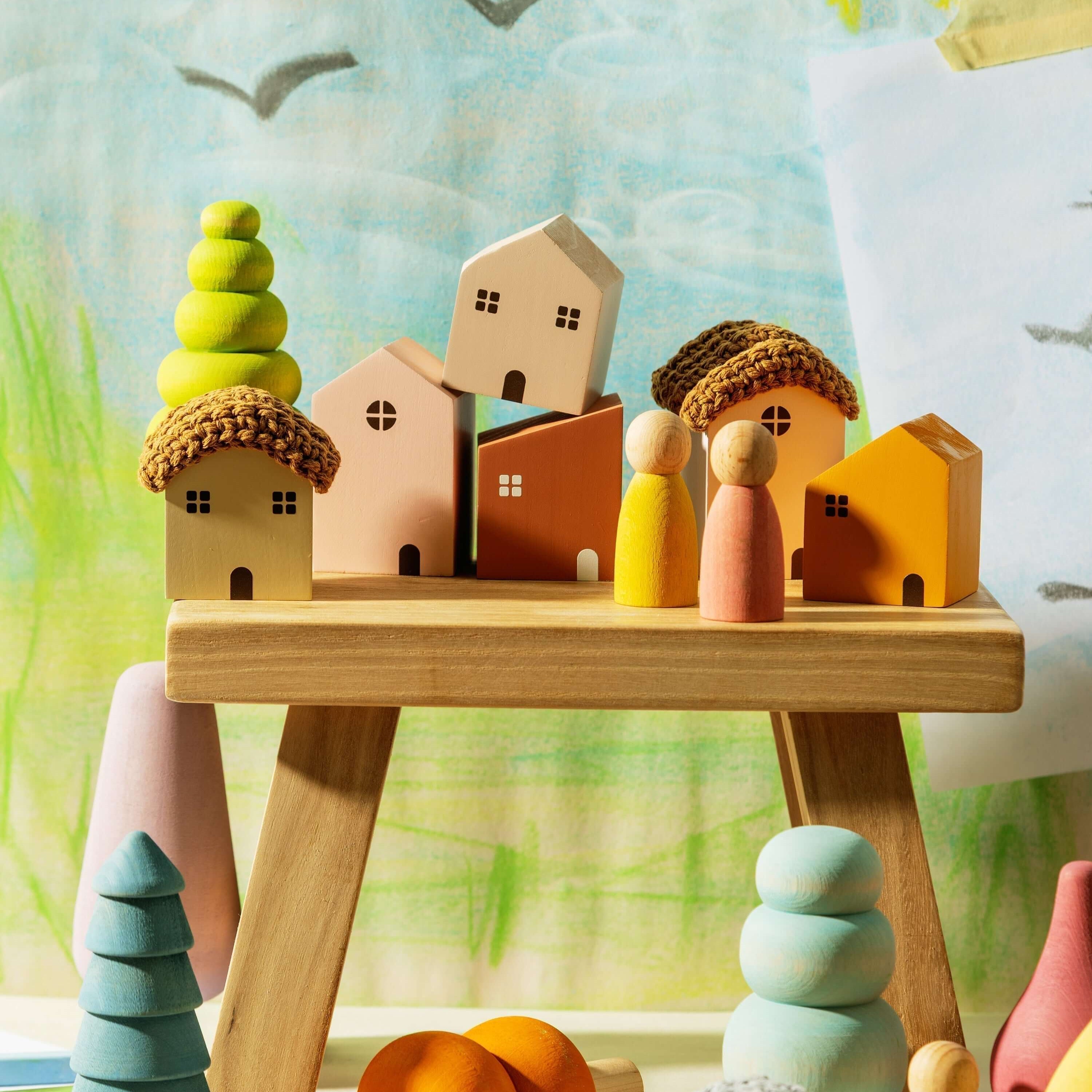 Montessori toy labels displayed on a wooden table with colorful figures and houses against a vibrant background.