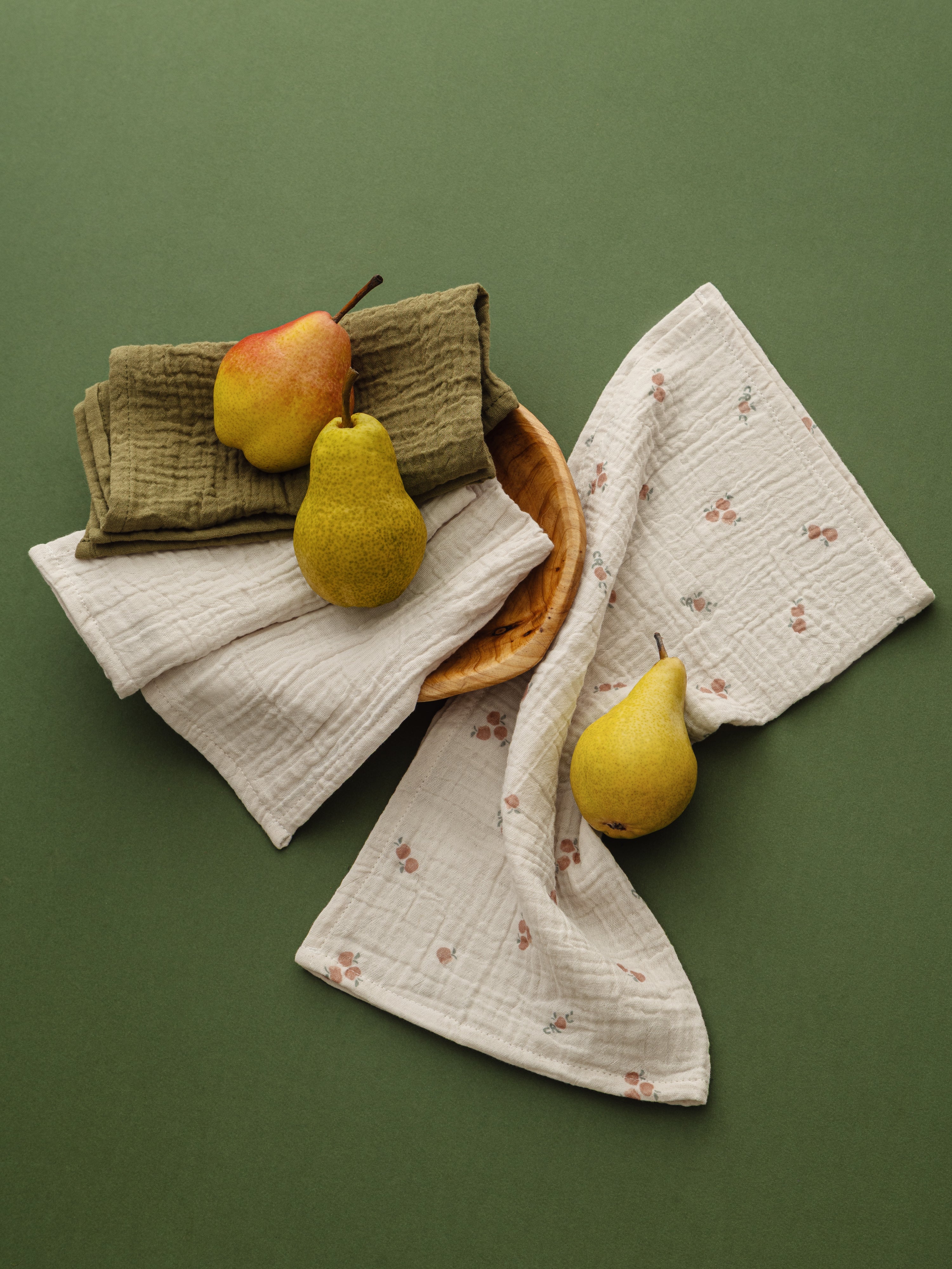 Three pears on fabric cloths against a green background