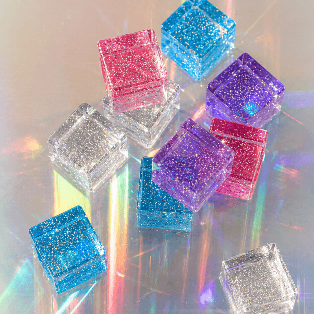 Colorful cosmic cube acrylic glitter blocks arranged with reflections and sparkle.