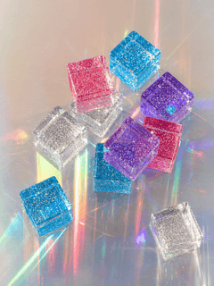 Colorful cosmic cube acrylic glitter blocks arranged with reflections and sparkle.