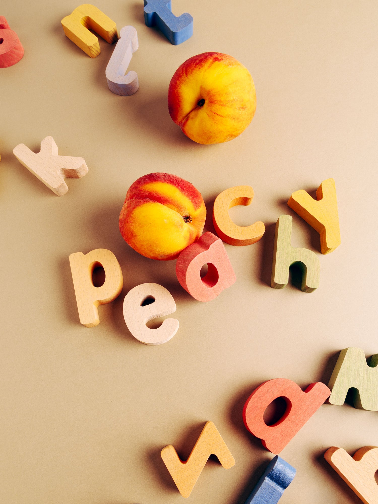 Colorful wooden letters scattered around peaches, ideal for educational puzzle set exploration.