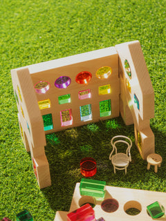 Rêve House Set modular wooden building set with colorful transparent windows and mini furniture on green grass.
