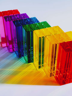 Illume Tower acrylic stacking blocks in a rainbow arrangement showcasing translucent colors and light reflection.