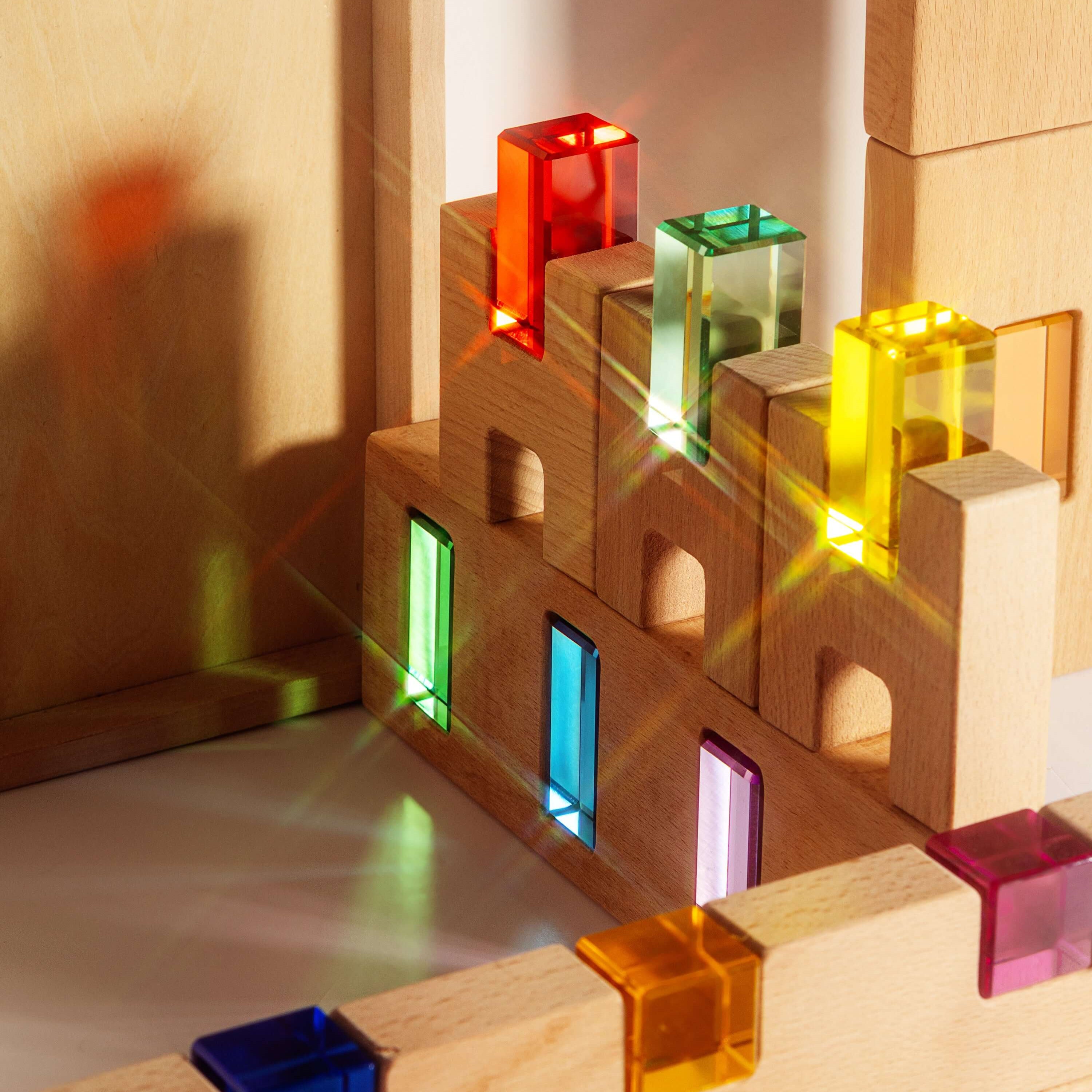 Fynn Set wooden building panels with colorful acrylic window inserts capturing sunlight.