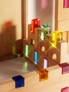 Fynn Set wooden building panels with colorful acrylic window inserts capturing sunlight.