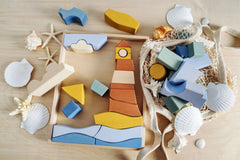 Byron Lighthouse Puzzle pieces arranged on a wooden surface with seashells and coastal colors.