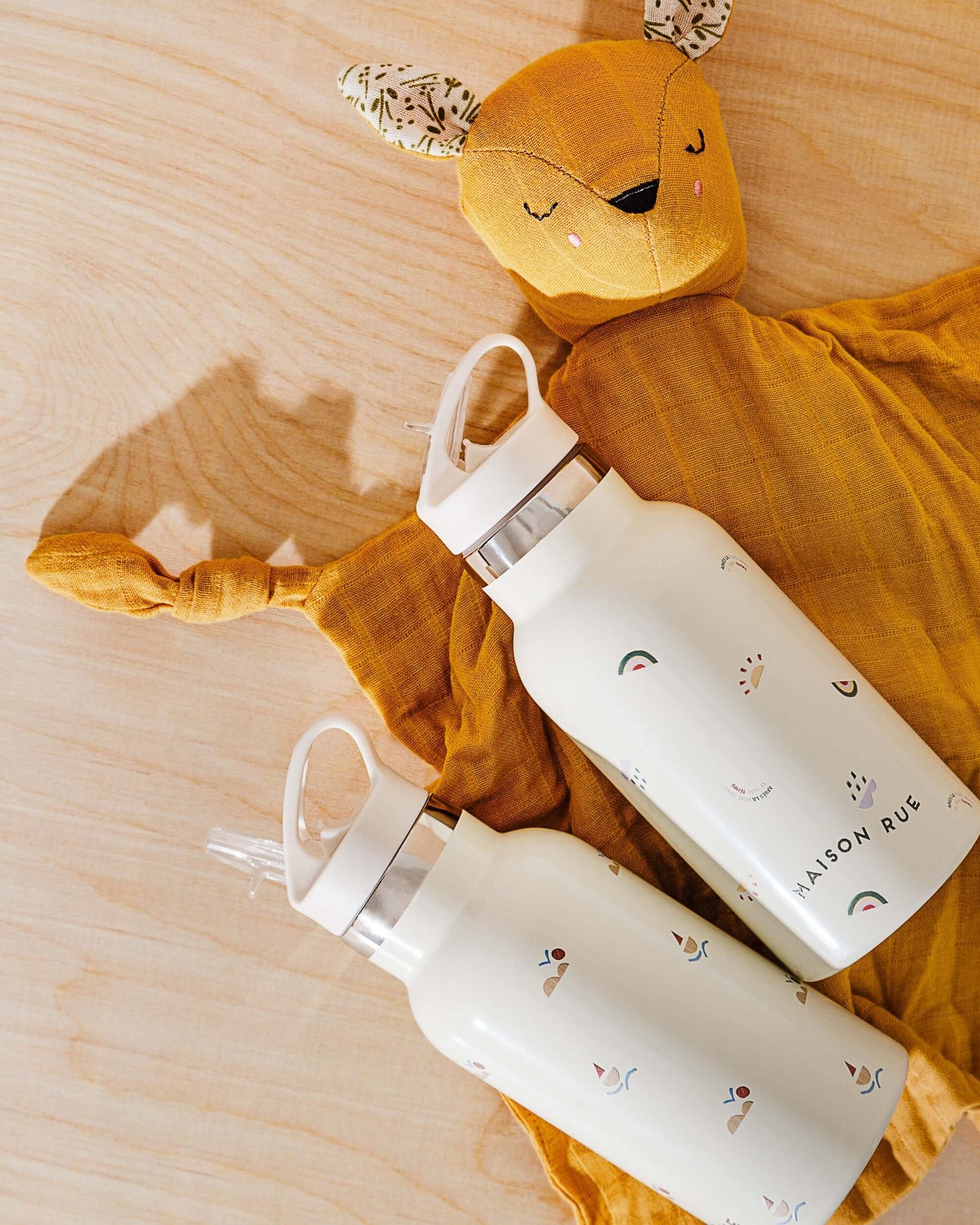 Pocket Pals organic cotton squirrel lovey comforter with fern print pocket pouch, shown with two baby bottles on mustard comforter