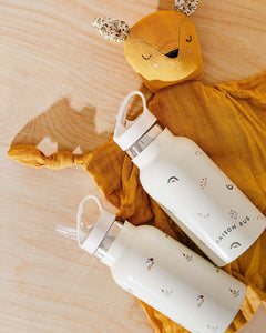 Pocket Pals organic cotton squirrel lovey comforter with fern print pocket pouch, shown with two baby bottles on mustard comforter