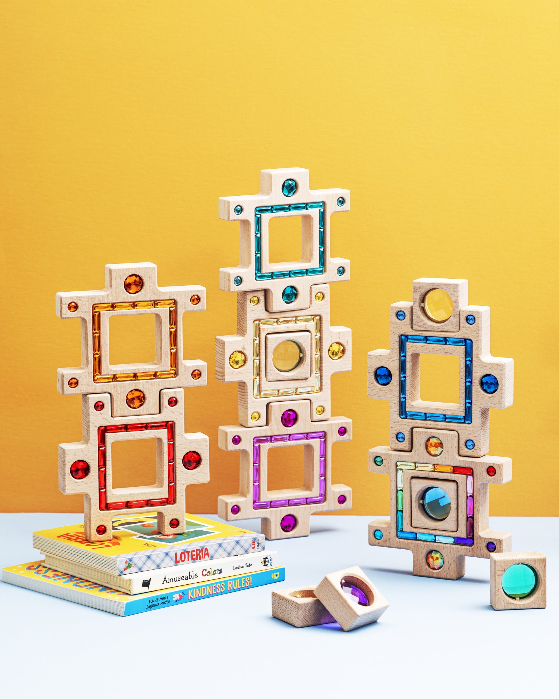 Colorful wooden blocks from the grand building collection set arranged playfully against a bright yellow background.