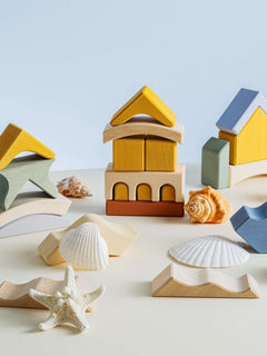 Colorful wooden building blocks and shells creating a stack, inspired by the Malibu Puzzle design.