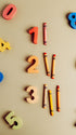 Colorful wooden number pieces and crayons arranged on a light beige background.
