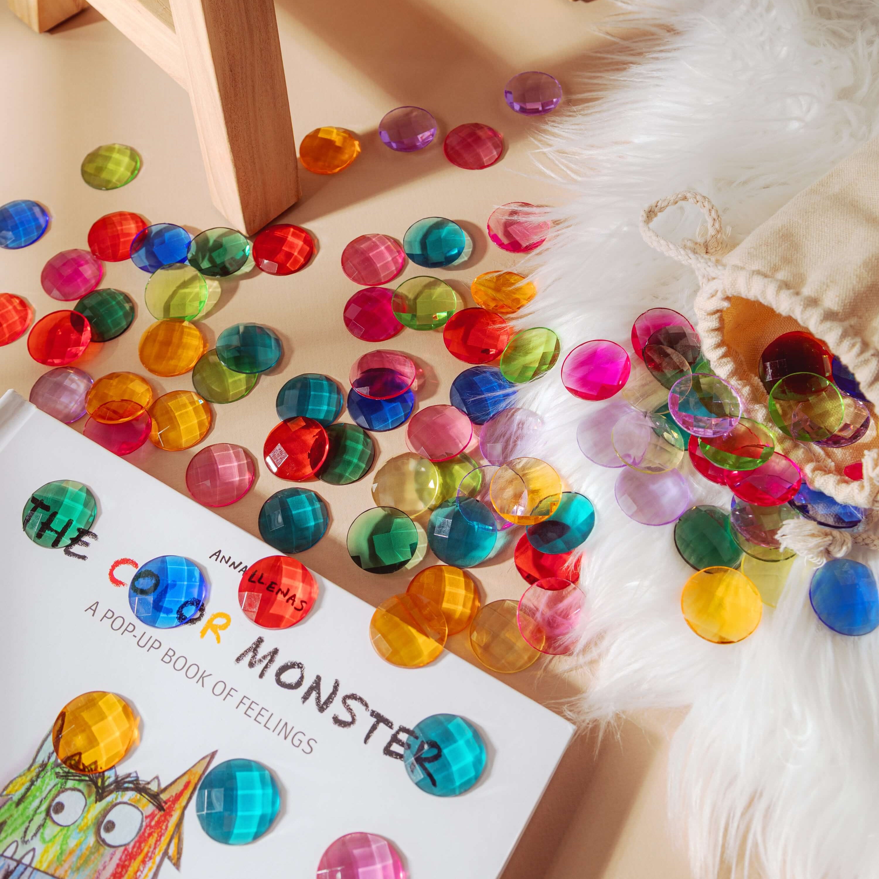 Colorful Enchanted Play Gems scattered around a children's book, perfect for sensory play and creative exploration.