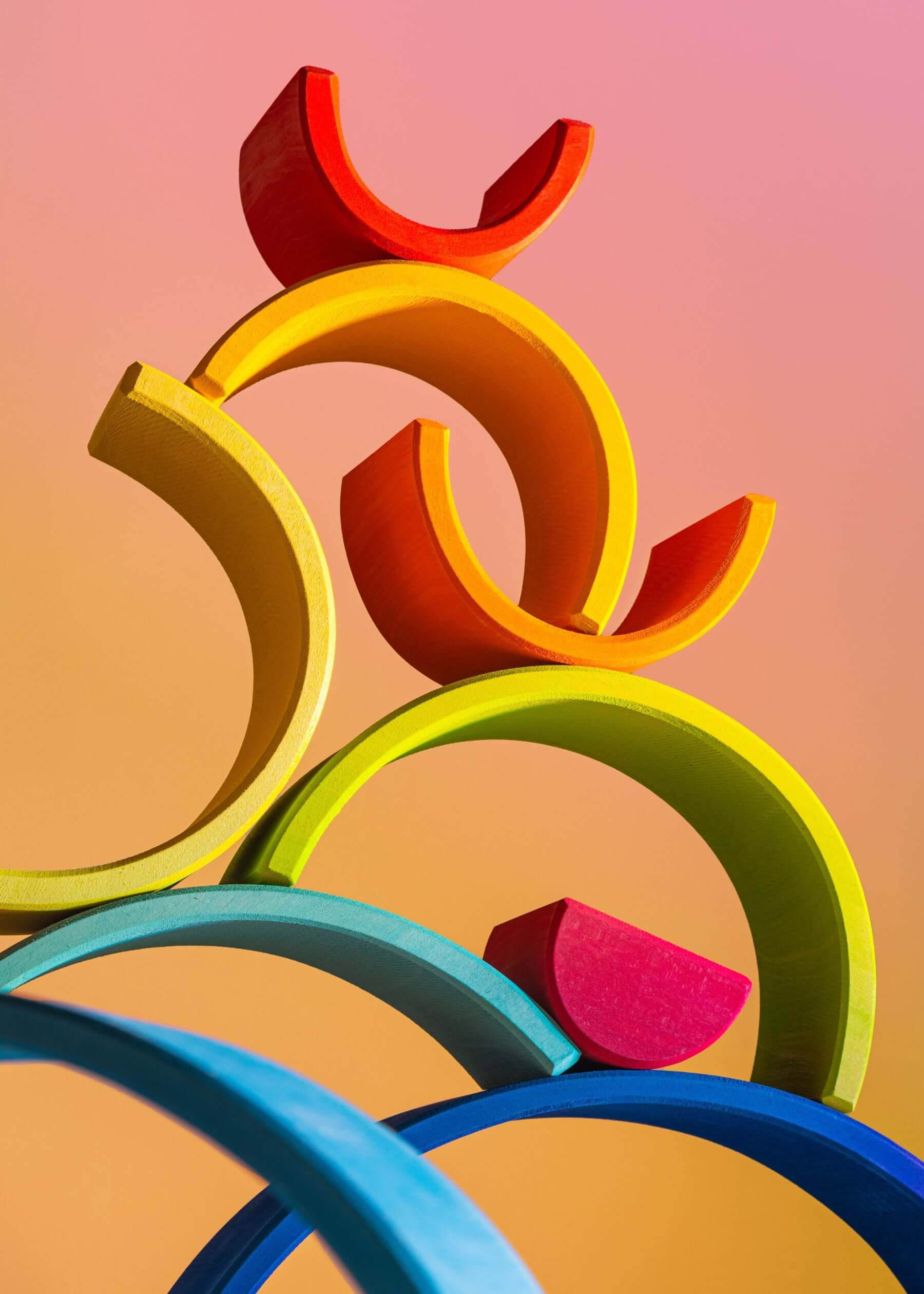Colorful arches from the Large Wooden Rainbow stacked playfully against a soft gradient background.