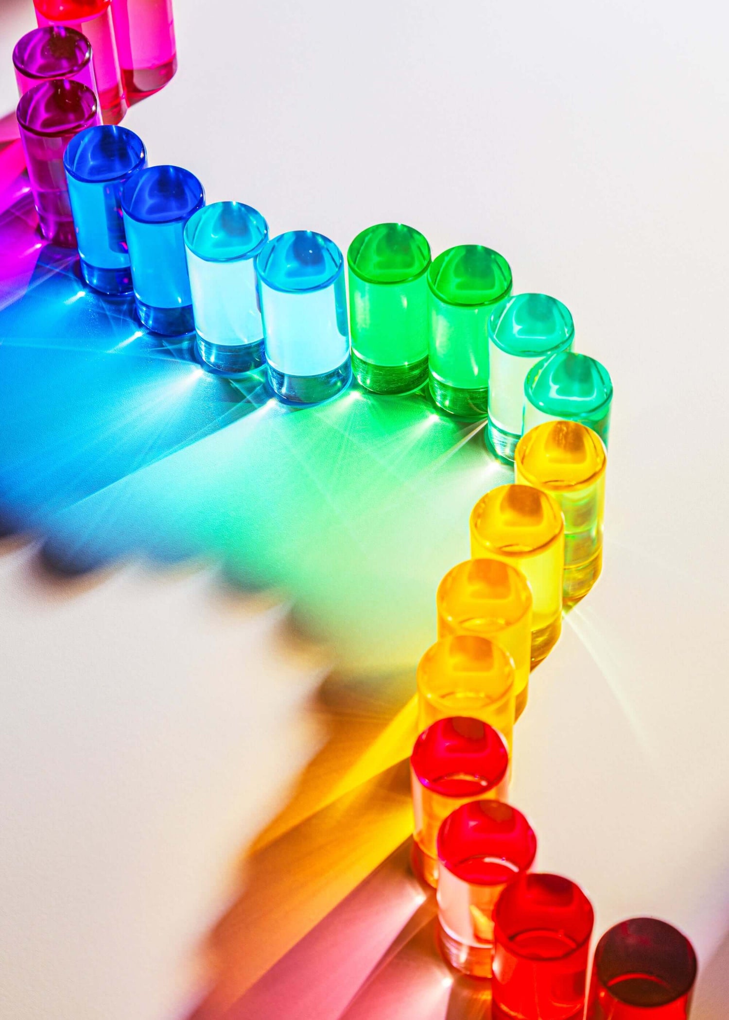Colorful lucite blocks arranged in a rainbow pattern on a white surface.