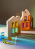 Wooden house models with colorful transparent windows on a reflective surface.