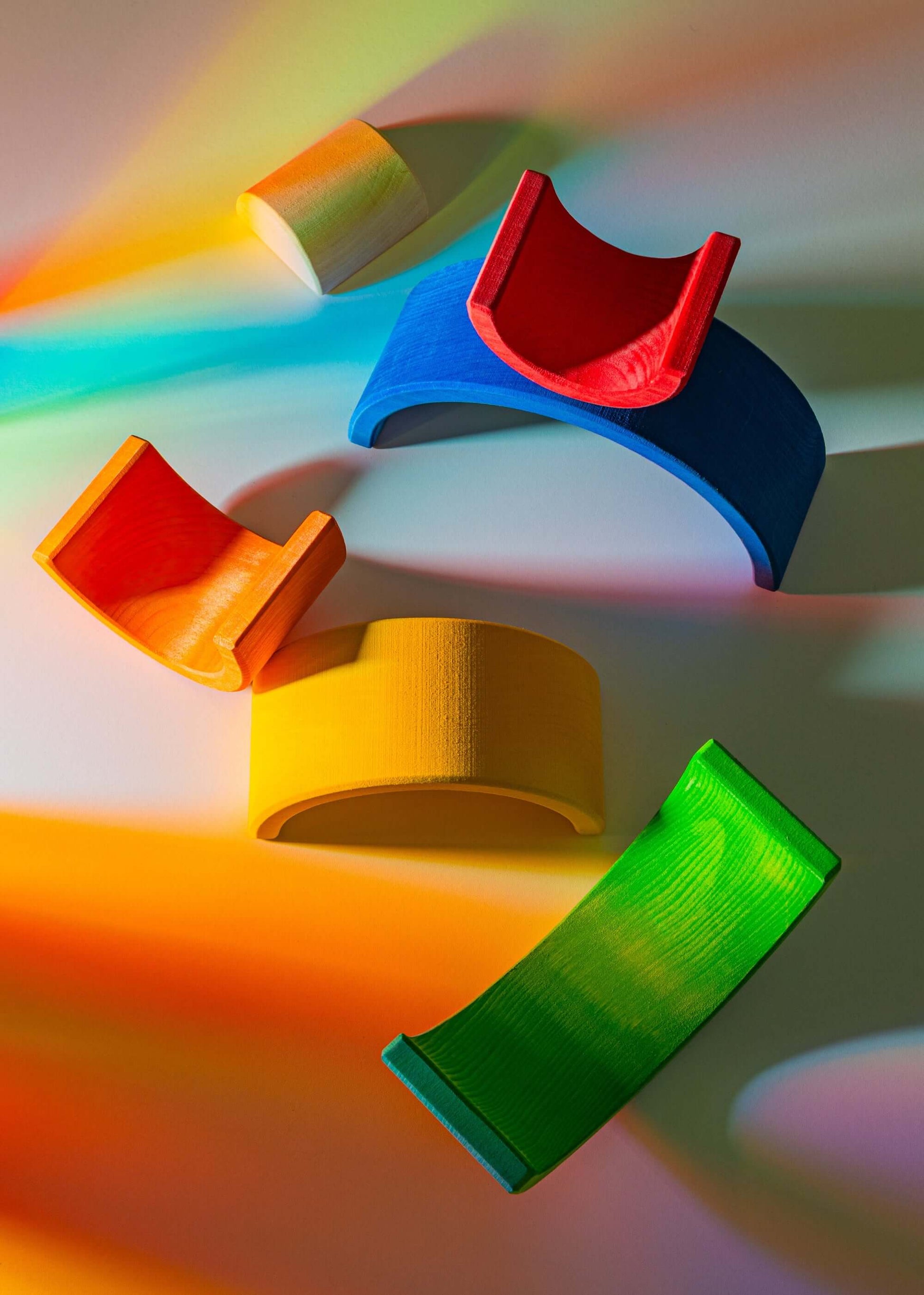 Small Wooden Rainbow with vibrant arches in red, yellow, blue, and green against a colorful background.