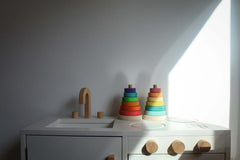 Suki Stacking Tower wooden rainbow stacking rings toy in primary colors on kids play table, toddler fine motor skills